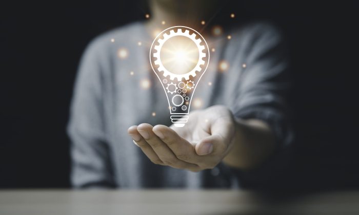 On the hand of a women with icon a light bulb And there is a gear icon on it. bright light bulb is idea innovation creativity inspiration brainstorming and imagination. technology education intellectual symbol future invention strategy energy light brain development science genius.